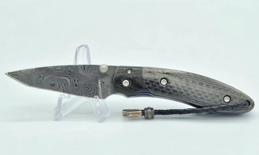 castlegate-manual-folder-2-375-416-layer-damascus-drop-point-blade-carbon-fiber-handle-scales-with-titanium-liners-black-micarta-bolster-custom-leather-sheath-liner-lock